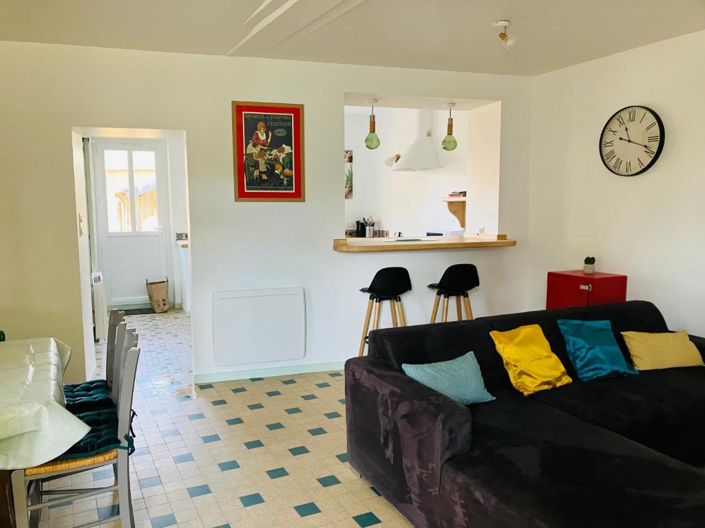 een woonkamer met een bank en een klok aan de muur bij Gîte les Tilleuls in Le Guédéniau