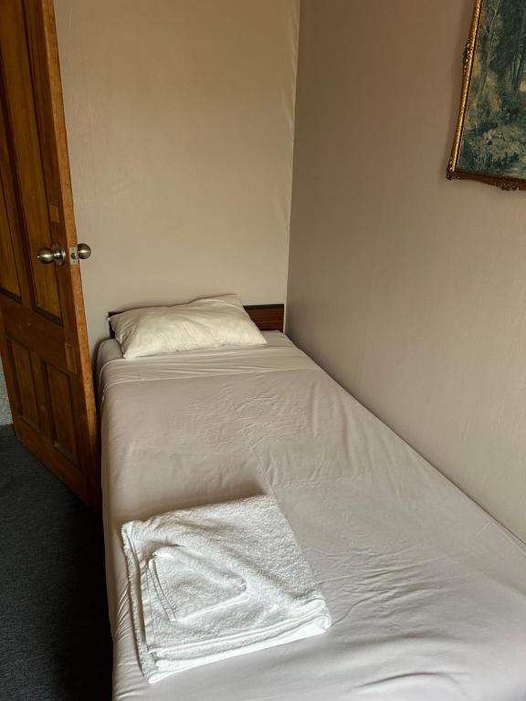 ein kleines Bett mit weißer Bettwäsche und einem Kissen in der Unterkunft Club Hotel Pahiatua in Pahiatua