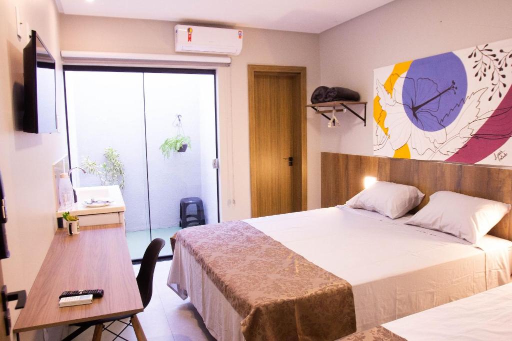 1 dormitorio con 2 camas, mesa y TV en Fiori Suítes, en Goiânia