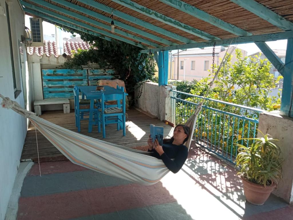 Eine Frau liegt in einer Hängematte auf einer Veranda in der Unterkunft Andrebyke terrace in Gergei