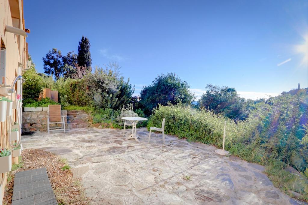a patio with a table and chairs in a garden at La farigoulette in Rayol-Canadel-sur-Mer