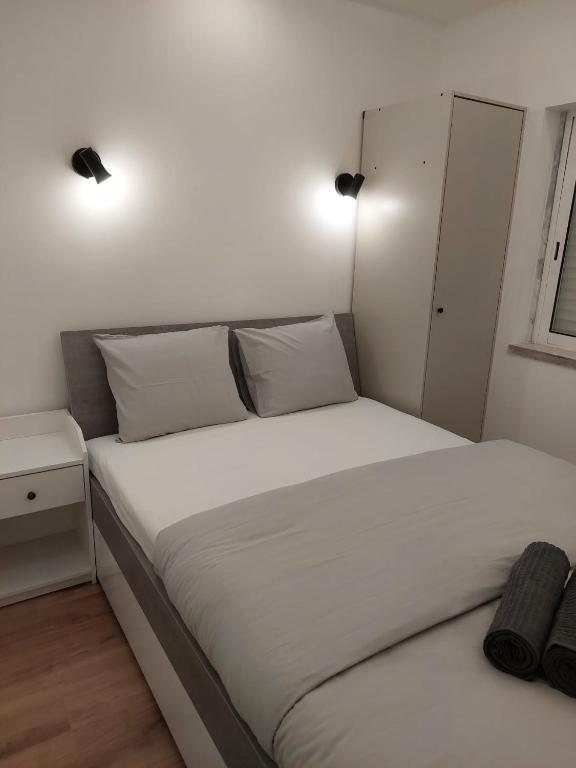 - un lit avec des draps et des oreillers blancs dans une chambre dans l'établissement Lisbon South Bay Rooms, à Almada