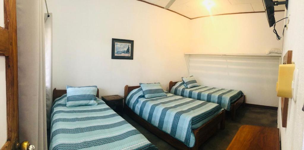 2 camas en una habitación con rayas azules y blancas en Hotel Del Aserradero, en Liberia