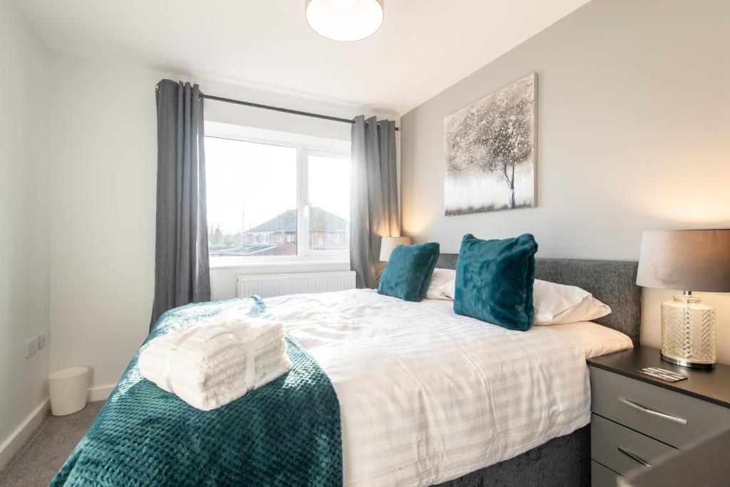 a bedroom with a bed with blue pillows and a window at No203 in Doncaster
