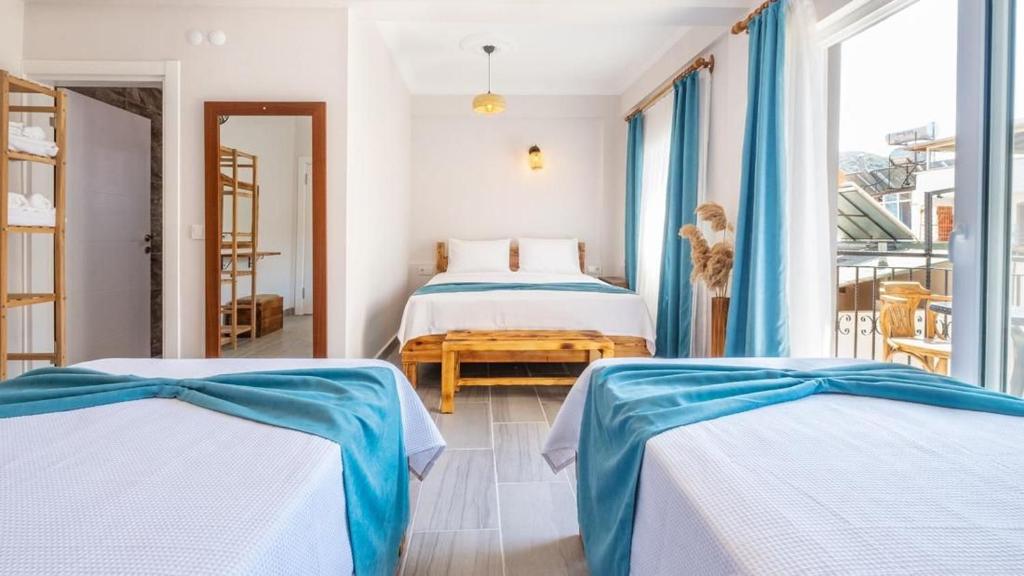 a bedroom with two beds with blue and white sheets at Larex Otel in Kaş