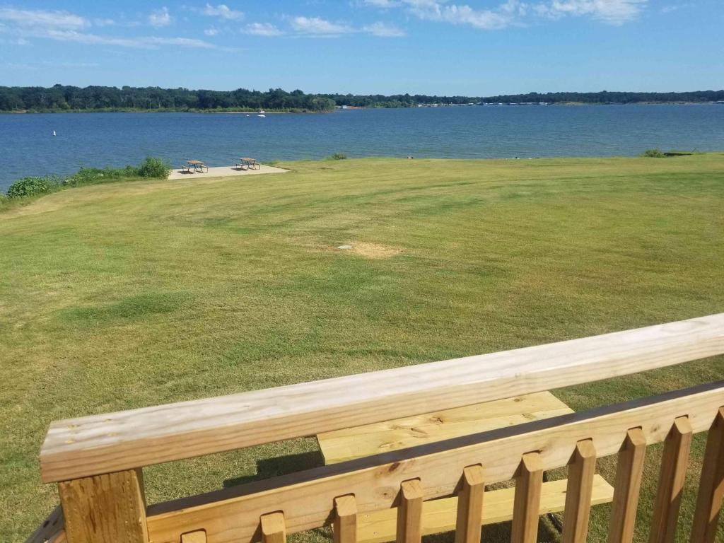 a wooden bench overlooking a large field of grass and water at Lakefront Cabin - The Willows - 11 in Mead