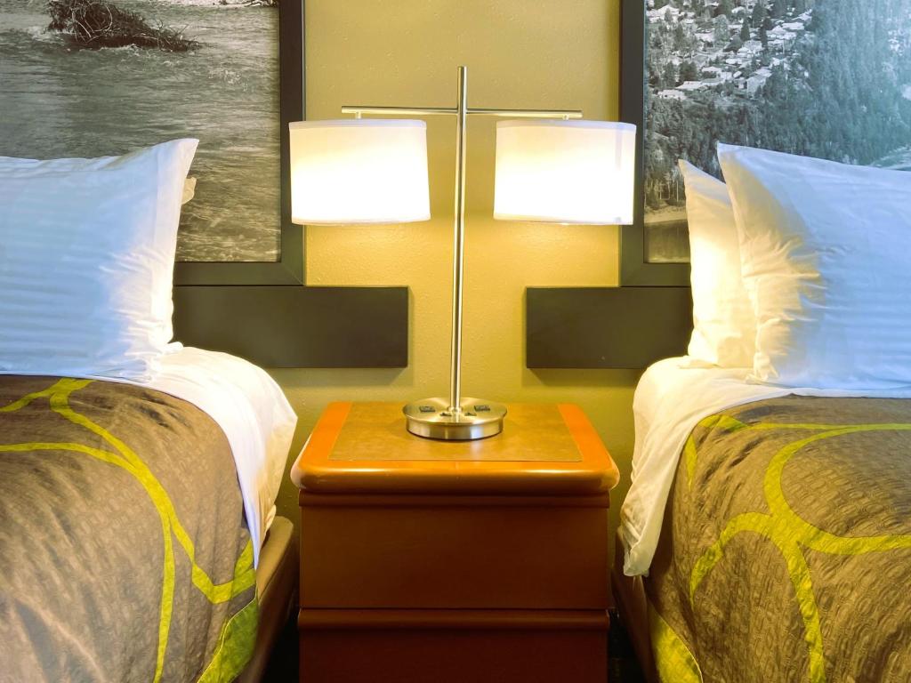 a hotel room with two beds and a table with a lamp at Super 8 by Wyndham Castlegar BC in Castlegar