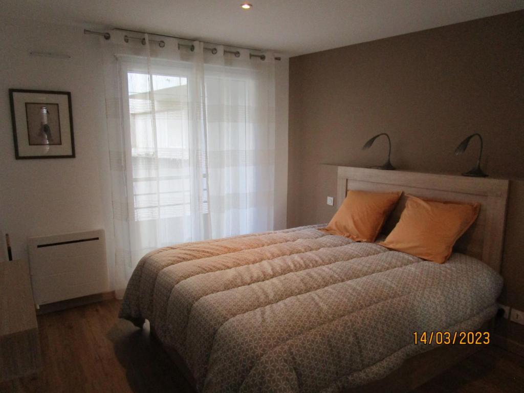ein Schlafzimmer mit einem Bett mit orangefarbenen Kissen und einem Fenster in der Unterkunft Très belle vue Canal du Midi in Béziers