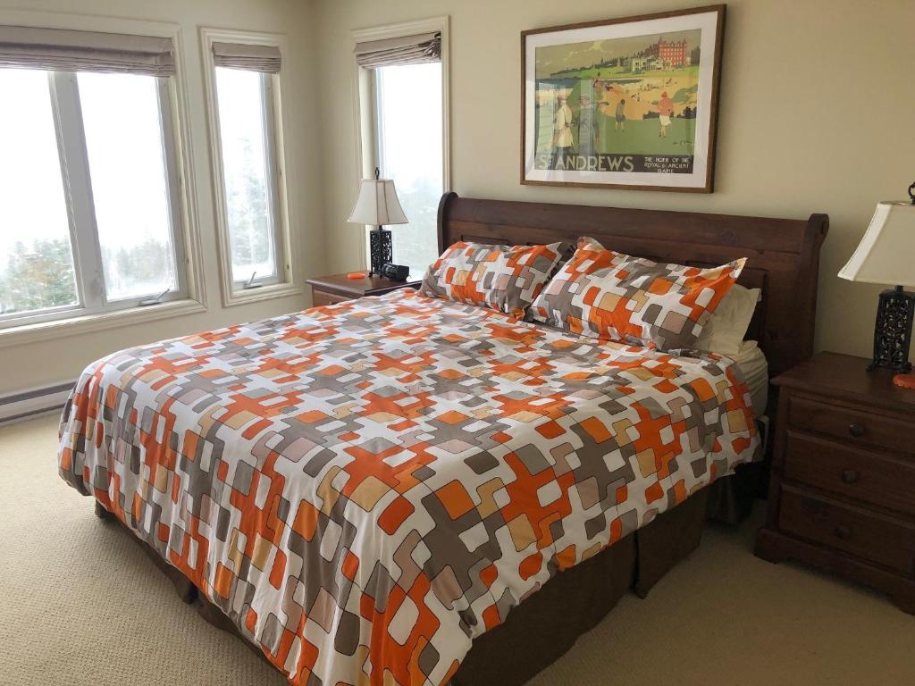 a bedroom with a bed with a colorful comforter and windows at The Thoughtful Dog Bed & Breakfast in South Brook