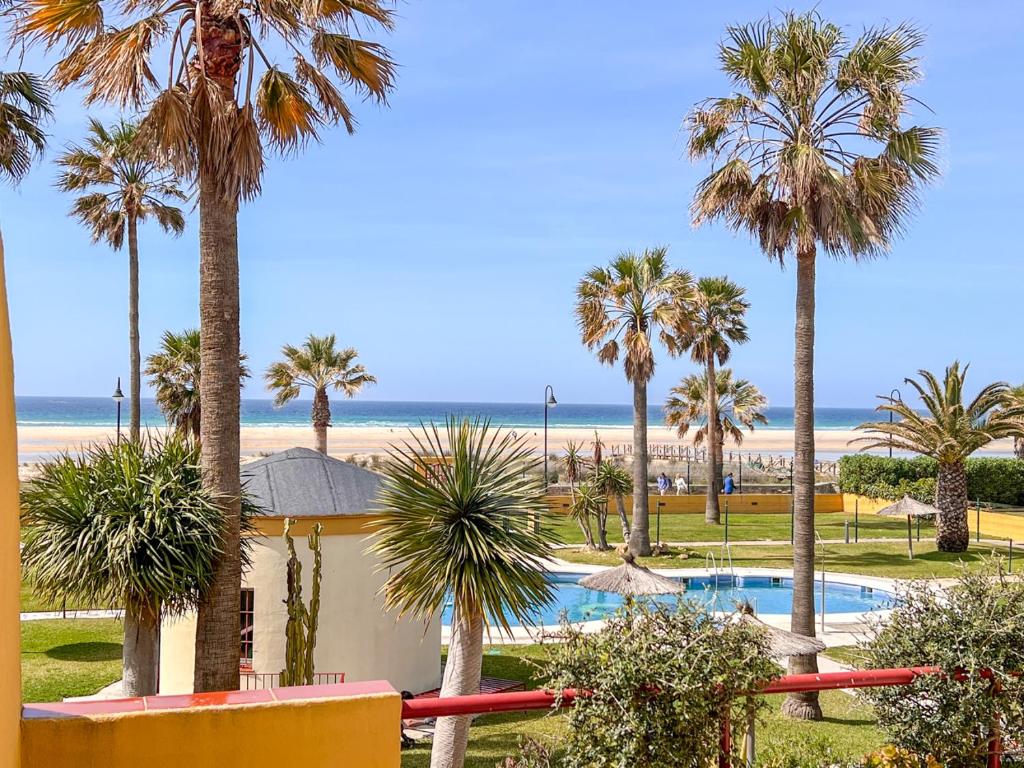 een uitzicht op het strand vanuit een resort met palmbomen bij Tarifa Cozy House PALM BEACH in Tarifa
