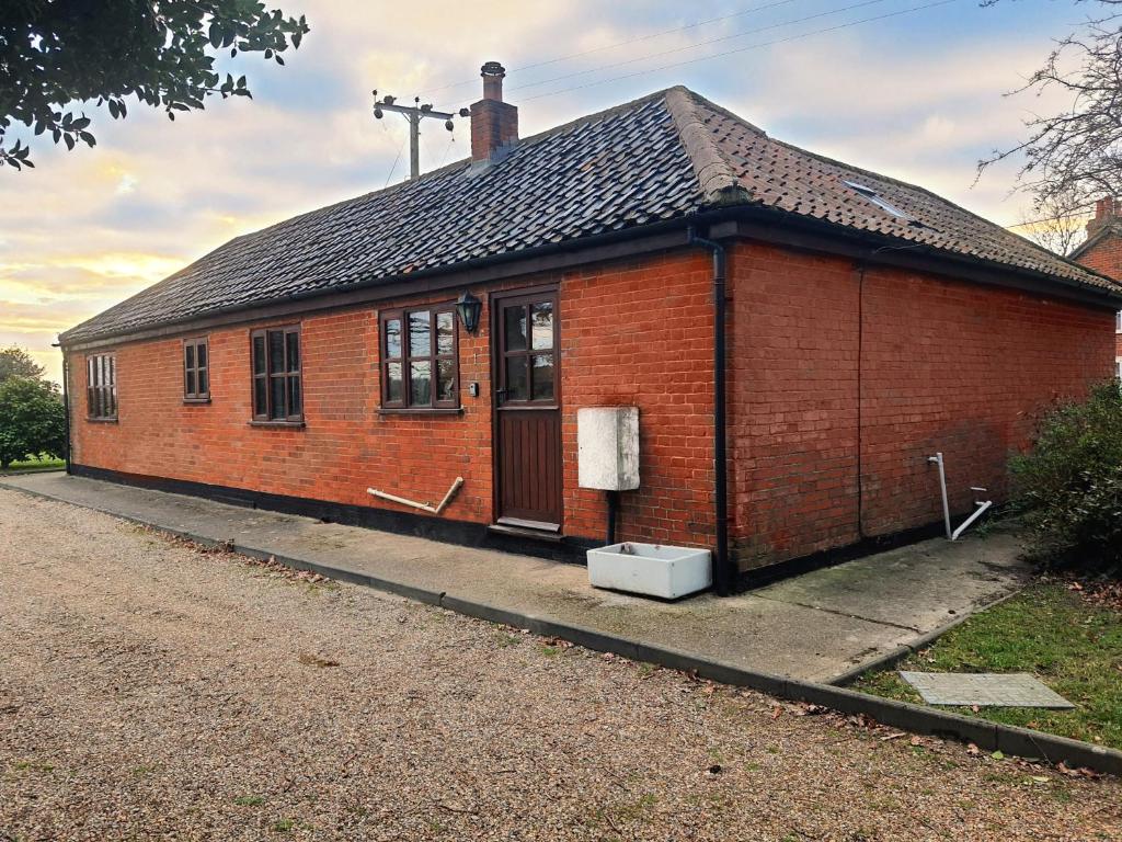 a red brick building with a door on a street at Cosy Barn Conversion 3BR (4 pax), Quiet, Close to Pin Mill 