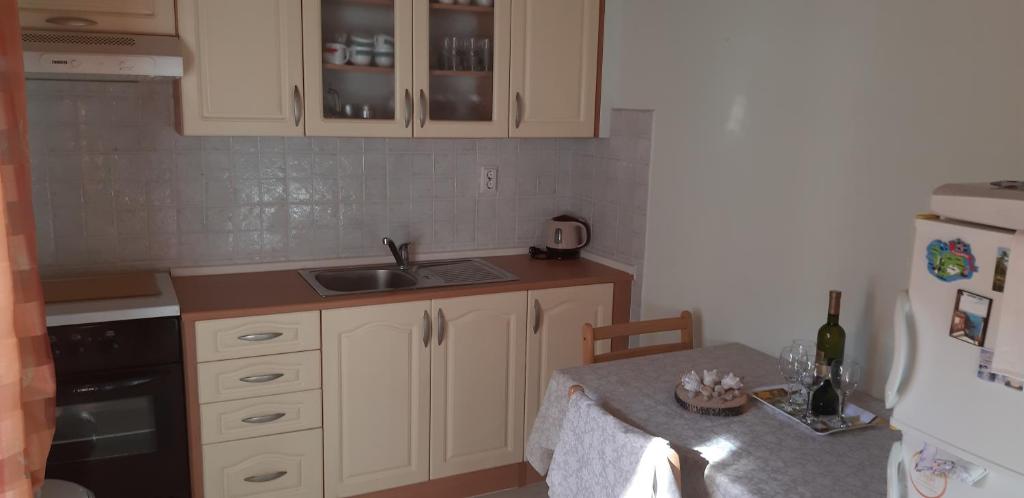 eine Küche mit weißen Schränken, einer Spüle und einem Tisch in der Unterkunft Apartman Bogdan in Jelsa