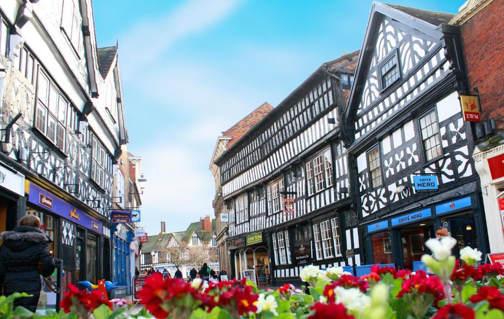 a group of buildings on a city street with flowers at Crown Hotel in Nantwich