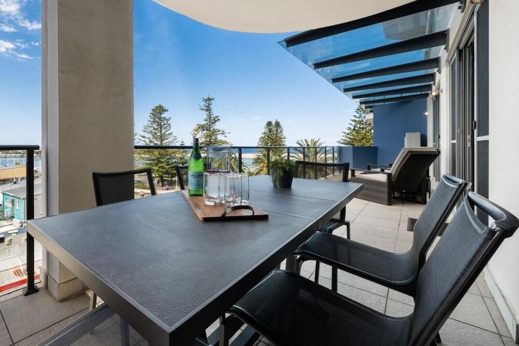 a table with two chairs and a bottle of wine on a balcony at Ocean View Spacious Luxury 3 Bedroom, Pool, Central, Walk everywhere 6PM CHECKOUT in The Entrance