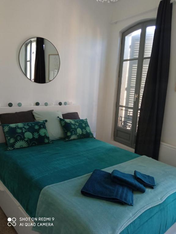 - une chambre avec un lit vert, un miroir et une fenêtre dans l'établissement Les terrasses, à Arles