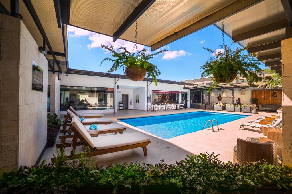 una piscina al aire libre con patio y una casa en KC Hotel San Jose, en San José
