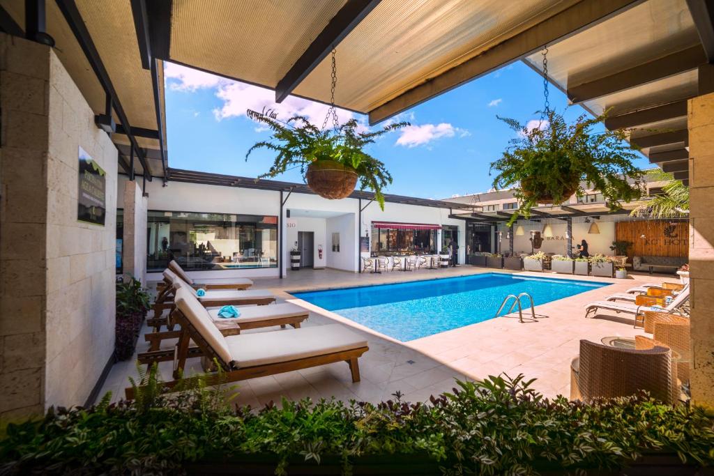 an outdoor swimming pool with a patio and a house at KC Hotel San Jose in San José