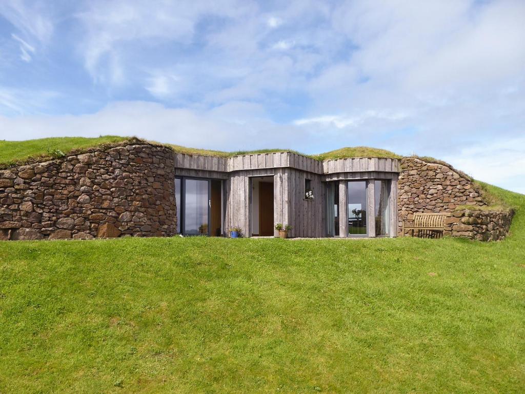 a stone house with a grass roof on a hill at High Trodigal in Machrihanish