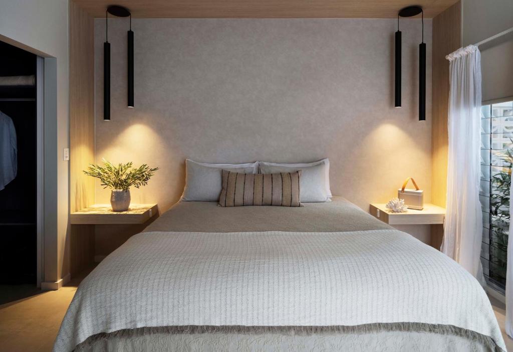 Tallowwood House Luxury Bed & Breakfast في ميناء ماكواري: غرفة نوم بسرير كبير مع مواقف ليلتين