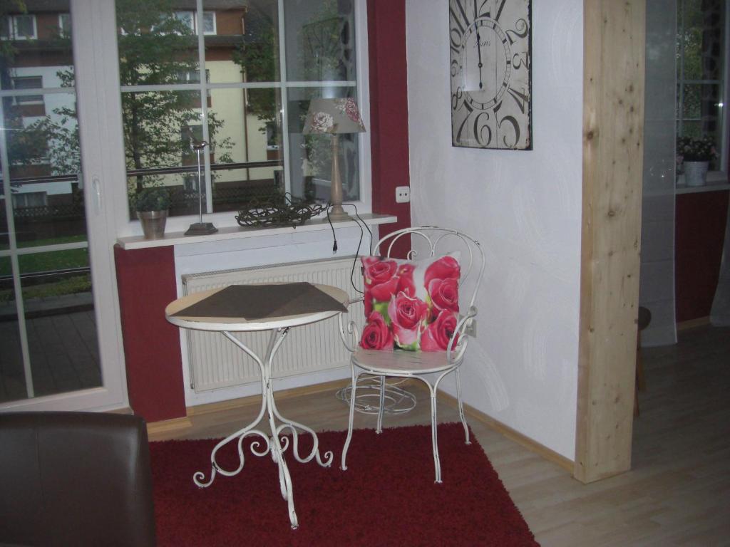 a table and a chair with a vase of roses at Endbach-Life in Bad Endbach