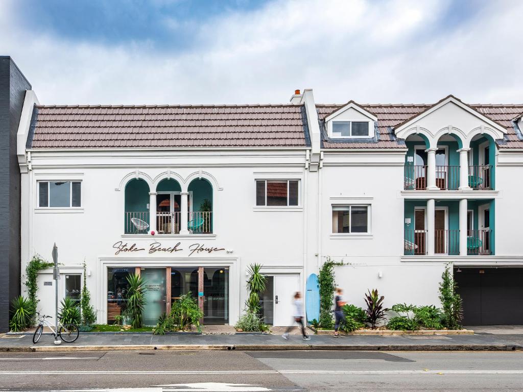 a white building with a sign on the front of it at Stoke Beach House in Sydney