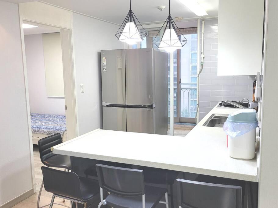 a kitchen with a counter with chairs and a refrigerator at Yeongtong Family House in Suwon