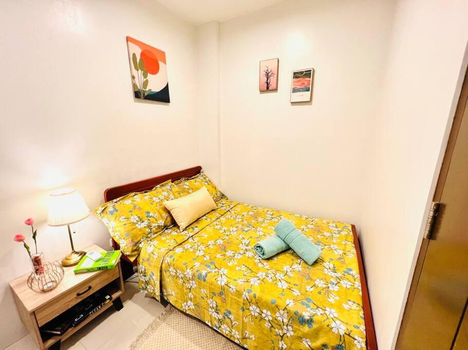 a bedroom with a bed with a yellow comforter at Iloilo Affordable Transient - near Iloilo Airport 