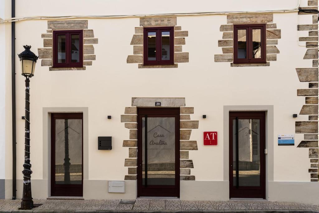 un edificio blanco con ventanas y luz de la calle en APARTAMENTOS CASA ARADIÑA, en Ríotorto