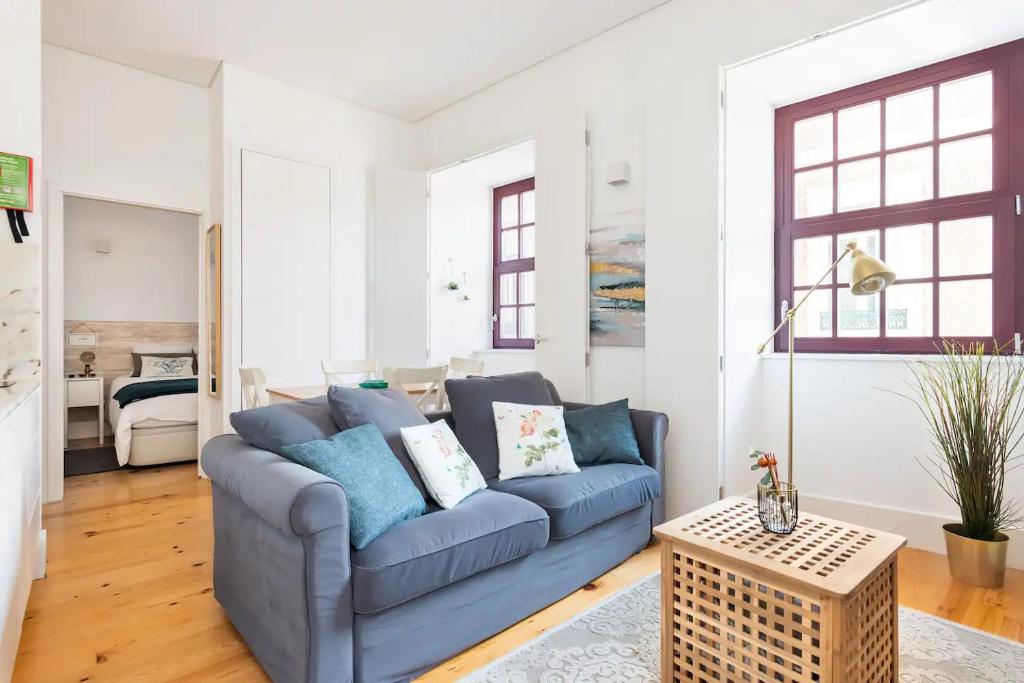 ein Wohnzimmer mit einem blauen Sofa und einem Tisch in der Unterkunft Neptuno Boutique Apartment - No coração do centro de Aveiro in Aveiro