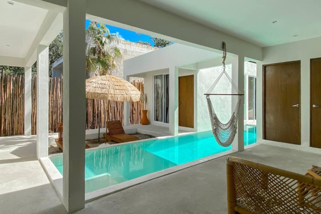 a swimming pool with a hammock in a house at Villa Kuxtah, Beautiful bungalow with Private Pool in Tulum