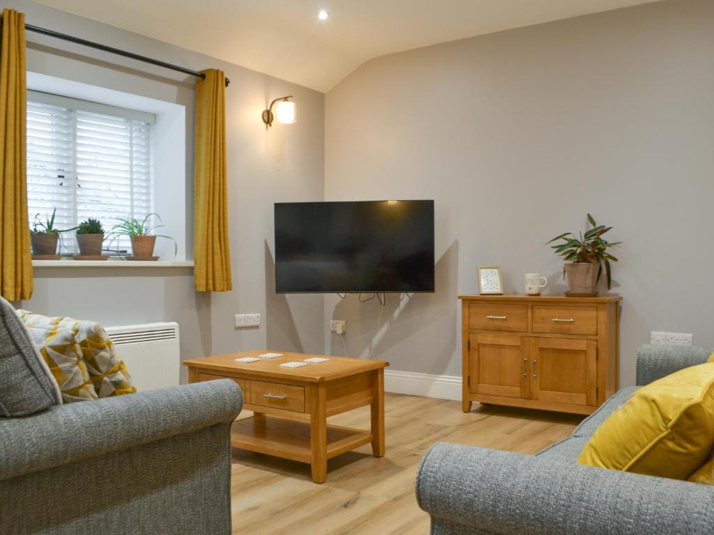 a living room with a tv and a couch and a table at Bumble Cottage in Cockermouth