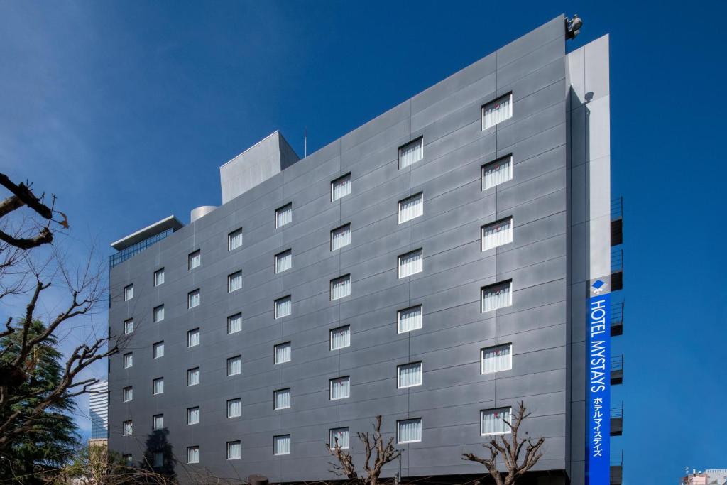 un gran edificio gris con un cartel. en HOTEL MYSTAYS Nishi Shinjuku, en Tokio