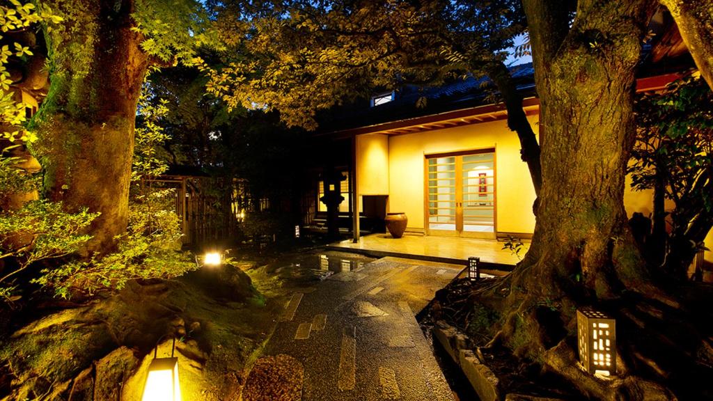 un árbol frente a una casa con luz en Kocho, en Kaga