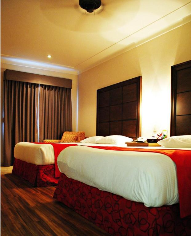 a hotel room with two beds with red and white sheets at HOTEL FIESTA NAVOJOA in Navojoa