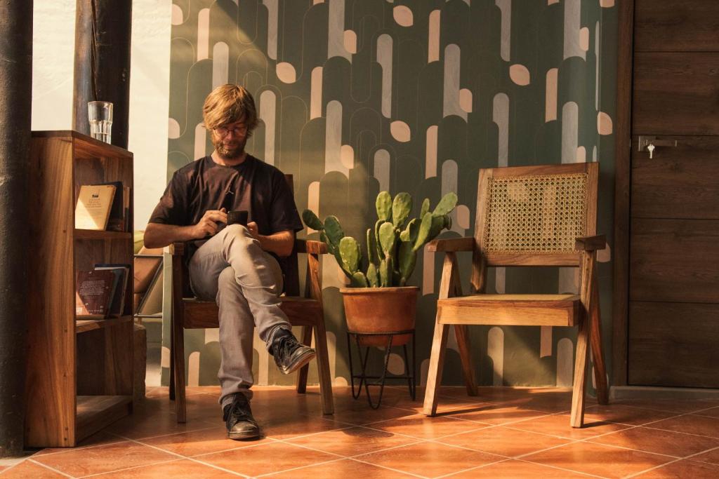 Flore Hostel في أنتيغوا غواتيمالا: رجل يجلس على كرسي أمام الجدار