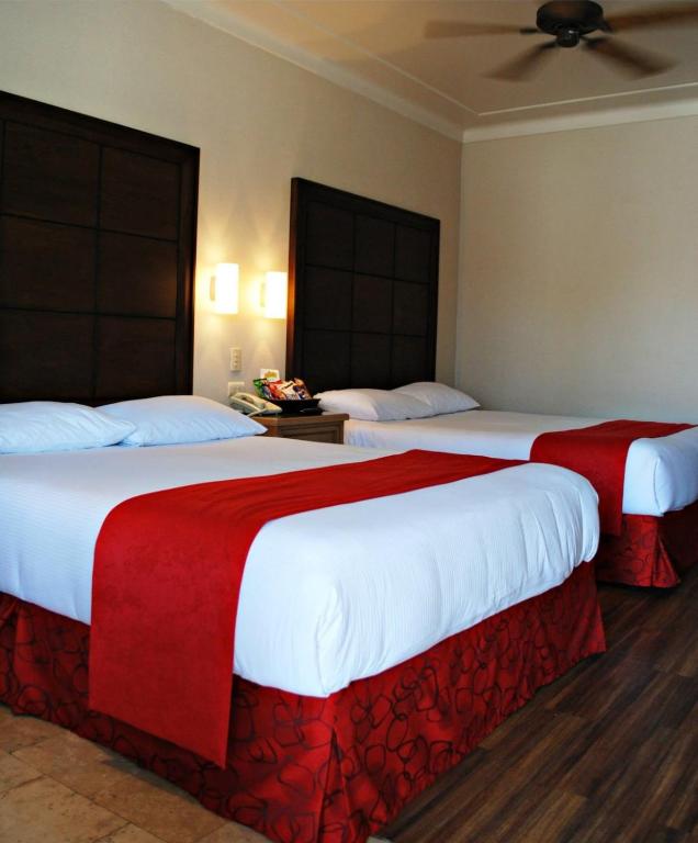 2 camas en una habitación de hotel con sábanas rojas y blancas en HOTEL FIESTA NAVOJOA, en Navojoa