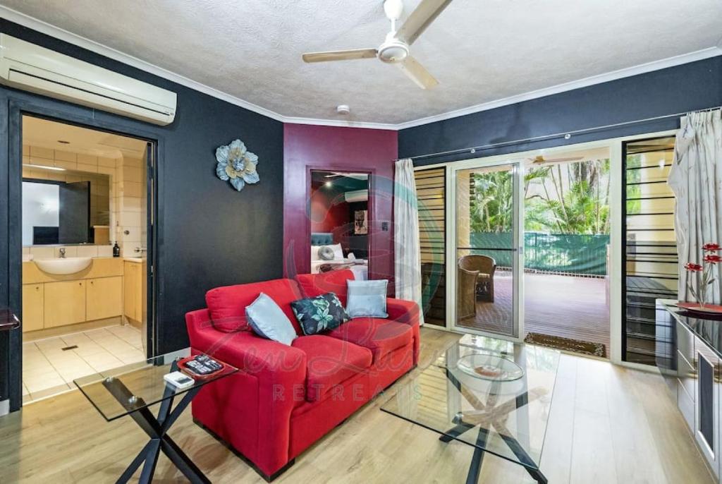 un sofá rojo en la sala de estar con ventilador de techo en ZEN MARKETS - Boutique 1-BR Apt Near Parap Markets en Parap