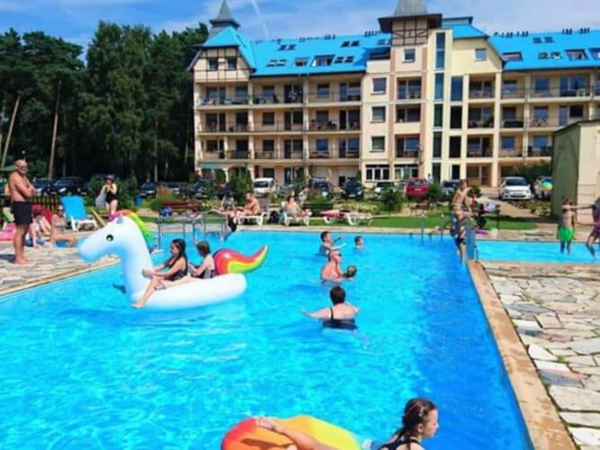 a group of people in a pool at a resort at Comfortable apartment, summer outdoor swimming pool, large garden, uk cin in Łukęcin