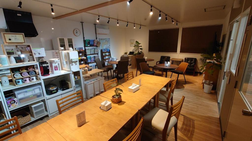 ein Restaurant mit einem großen Holztisch und Stühlen in der Unterkunft 宿 inn TEK-TEK in Sanuki