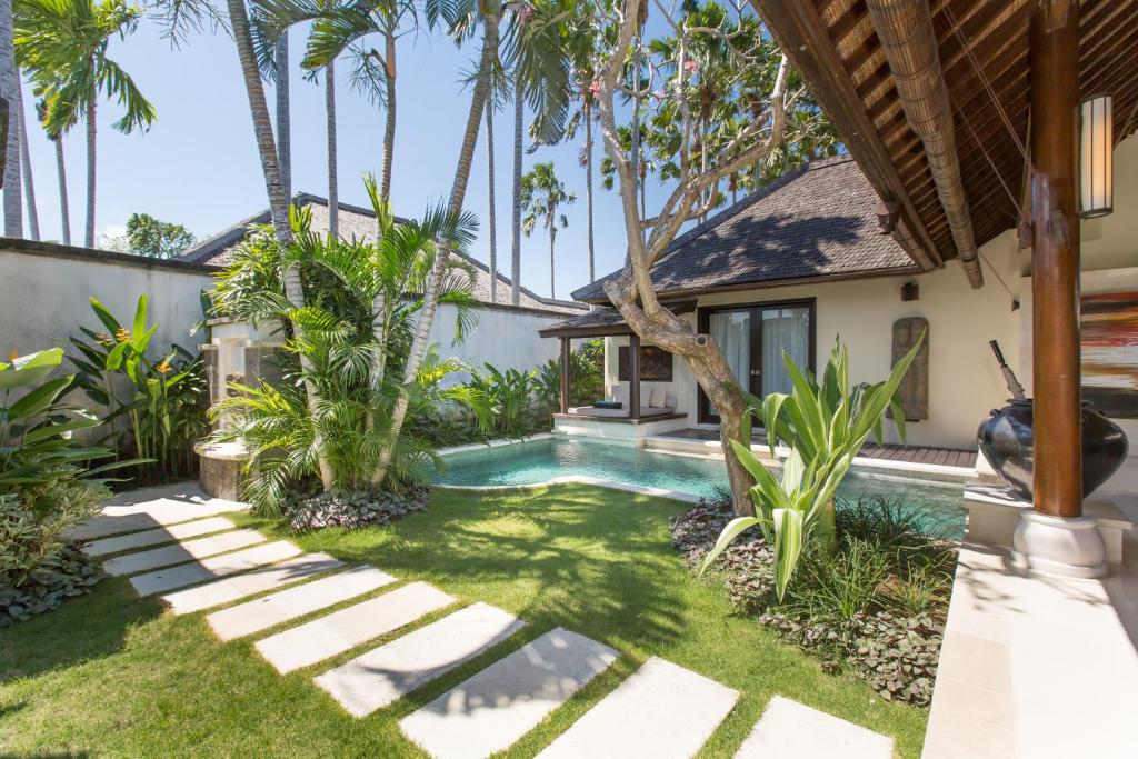 a villa with a swimming pool and palm trees at Villa Air Bali Boutique Resort and Spa in Seminyak