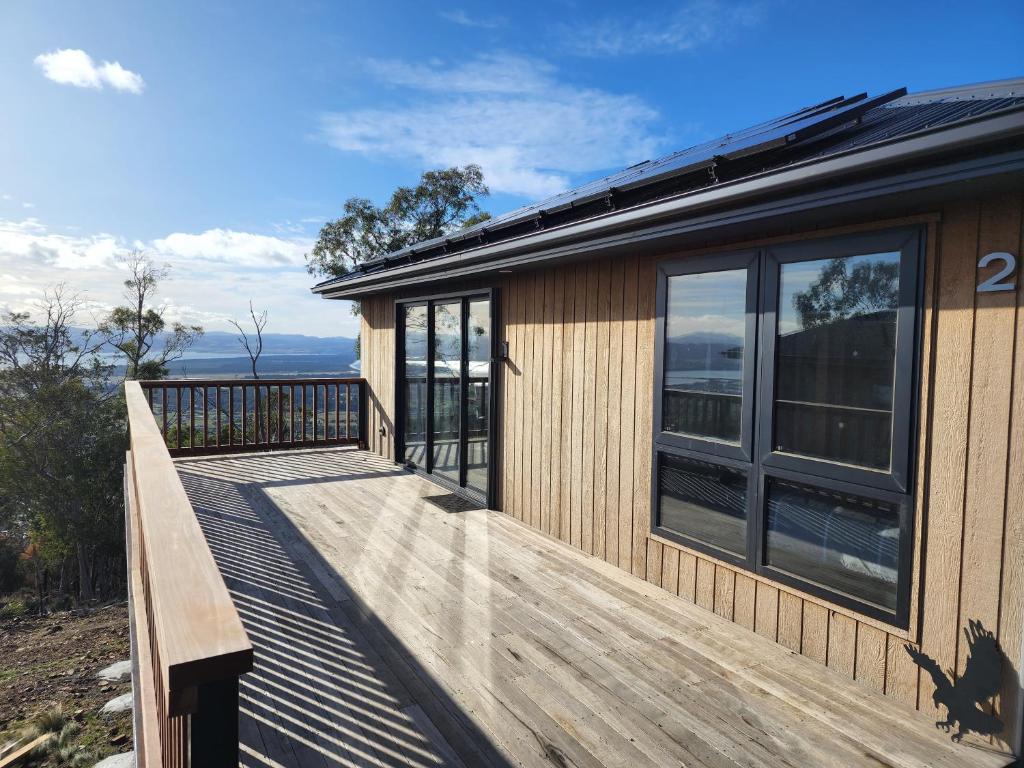 une terrasse en bois à côté d'une maison avec fenêtres dans l'établissement Mount Rumney Escapes Seaview House 2 - Eagle House, à Mount Rumney