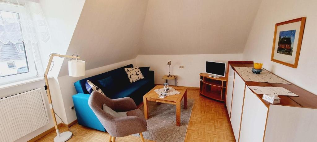 pequeña sala de estar con sofá azul y escritorio en FeWo-1-OG-links, en Böhl