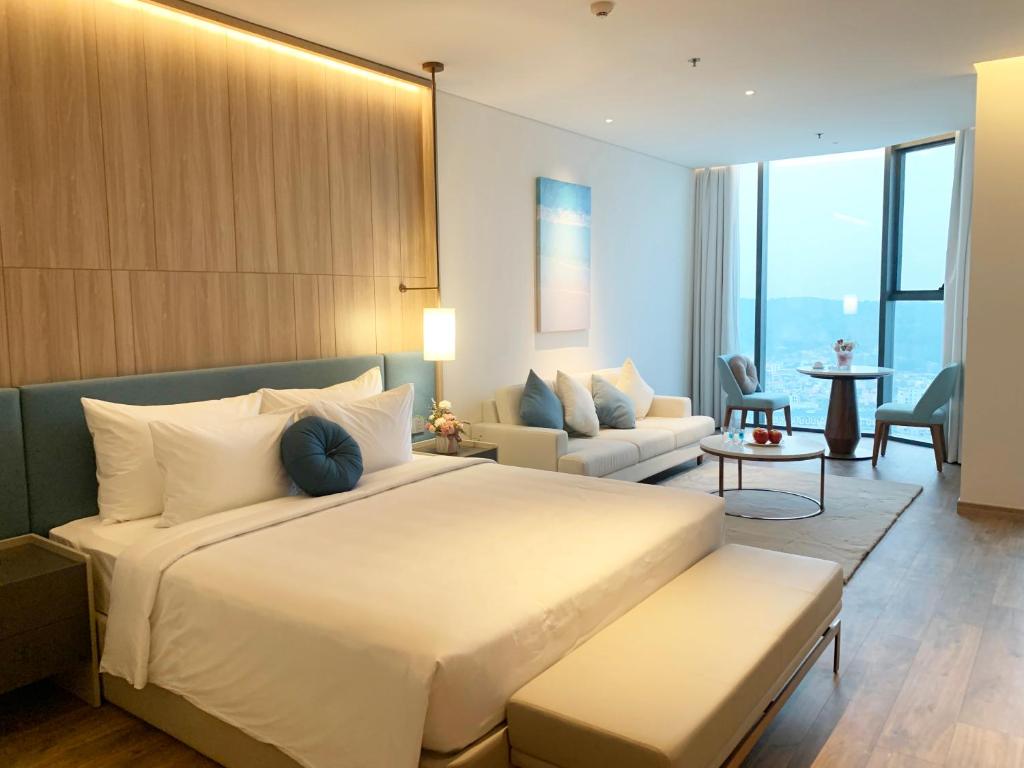 1 dormitorio con 1 cama grande y sala de estar en HB Serviced Apartment - Alacarte Hạ Long, en Ha Long