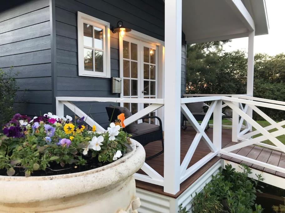 une maison avec un pot de fleurs sur la terrasse couverte dans l'établissement Hamptons In Rye Blue Cottage 3 Mins from Hot Springs!, à Rye