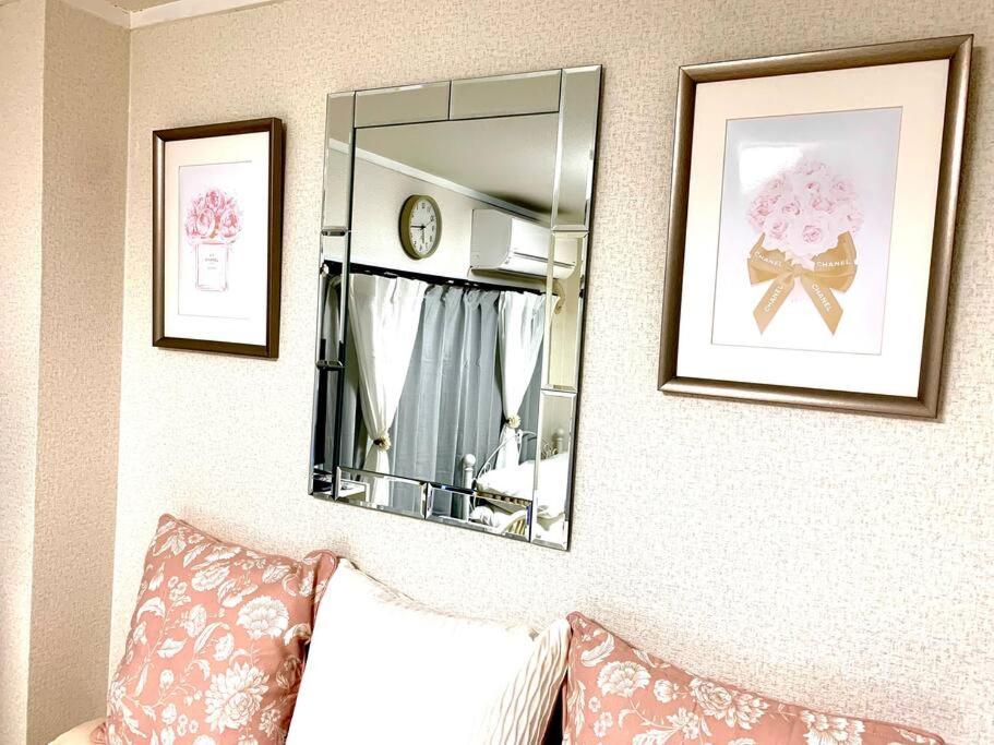un espejo en una pared con fotos y un sofá en COCO Nakameguro 202, en Tokio