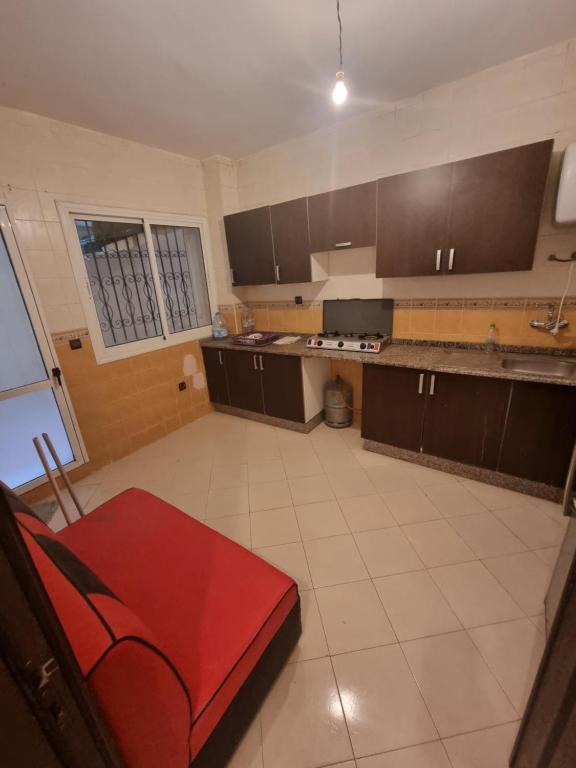 a large kitchen with brown cabinets and a red couch at Tanger ahlan in Tangier