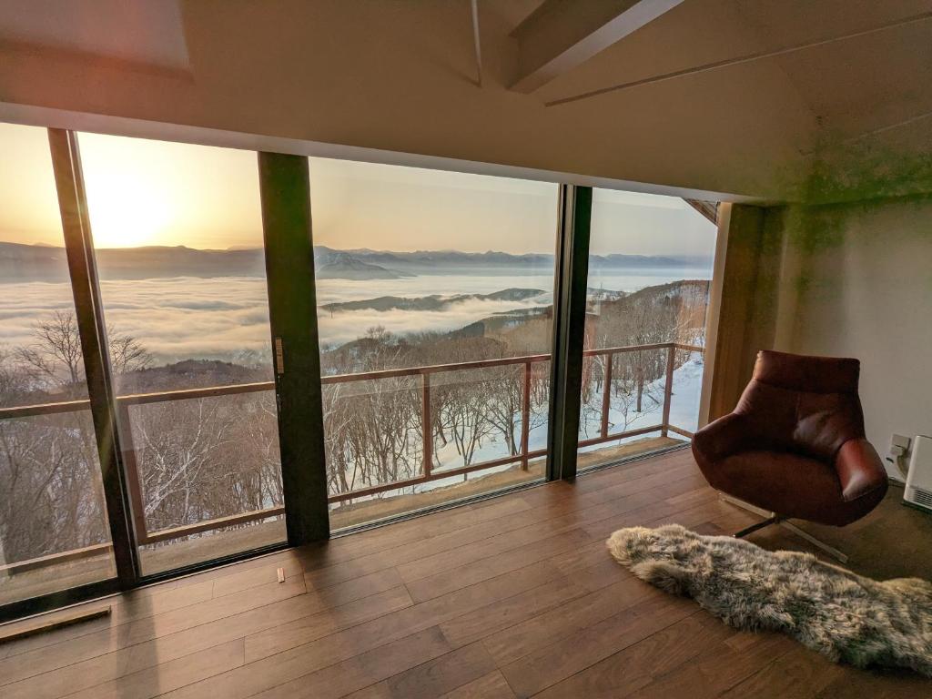 a room with a chair in a room with large windows at Aki's Apartments Madarao in Iiyama