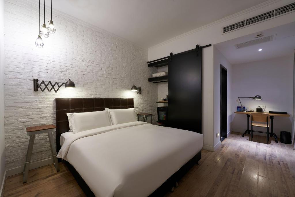 a bedroom with a large white bed and a table at Yi Stack Hotel Beijing in Beijing