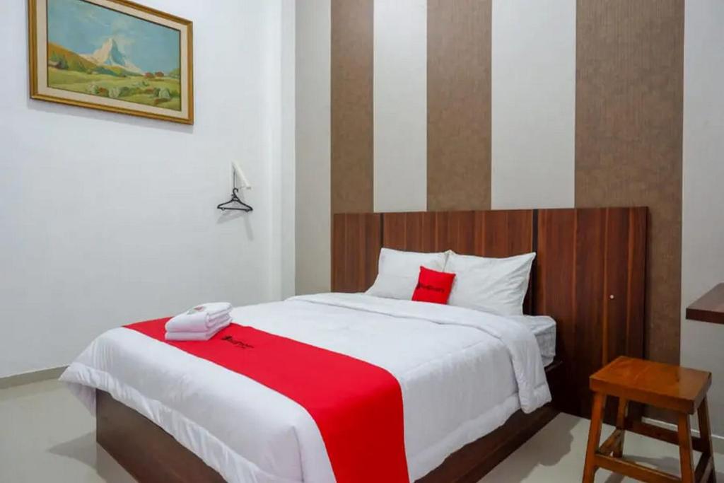 a bedroom with a large bed with a red blanket at RedDoorz near Stasiun Purwosari in Solo