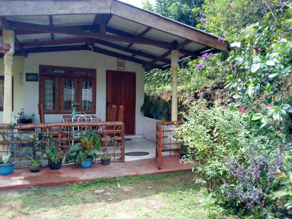 a porch of a house with a table and some plants at Ella j villa in Ella